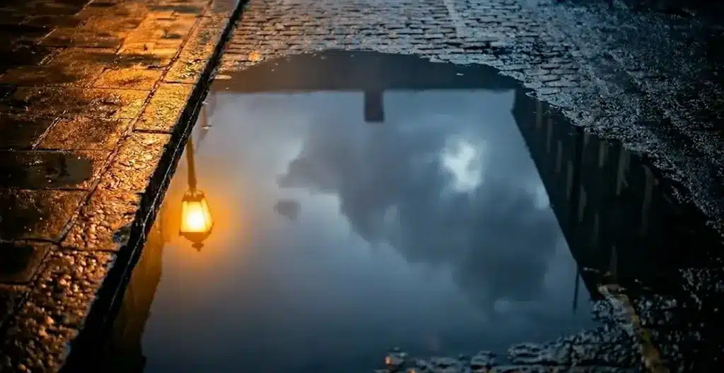 Still Here storyboard – puddle reflection Still Here AI short film: a gas lamp and a cloudy sky reflected in a rain puddle on a cobbled London street